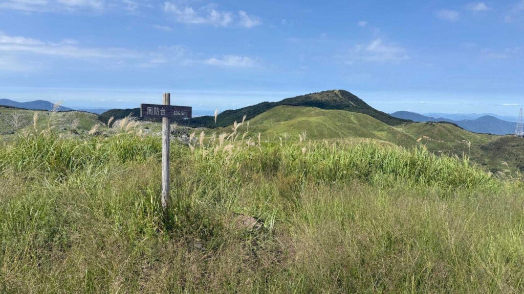 周防台方面を示す道標と緑の稜線パノラマ