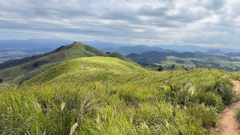 草原の尾根越しに広がる山々と集落の遠望