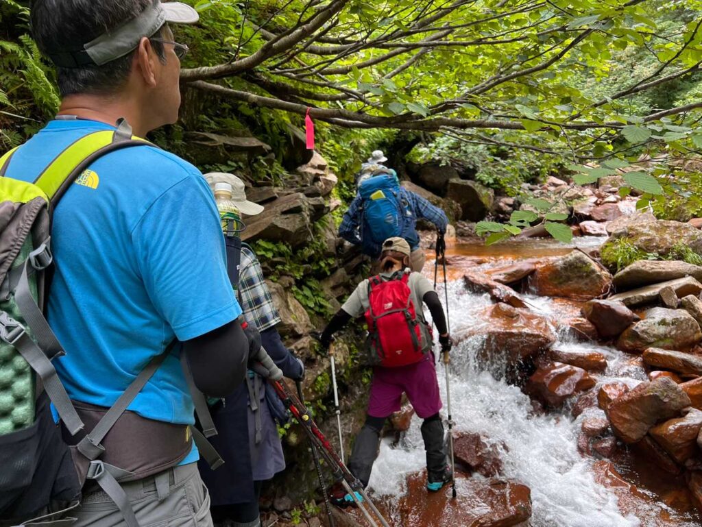 滝のそばを沢登りするグループ