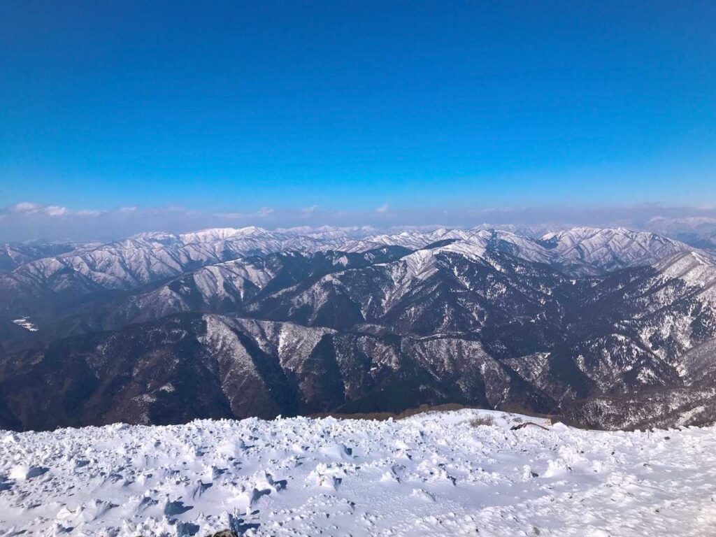 山頂からの雪をまとった山々の展望