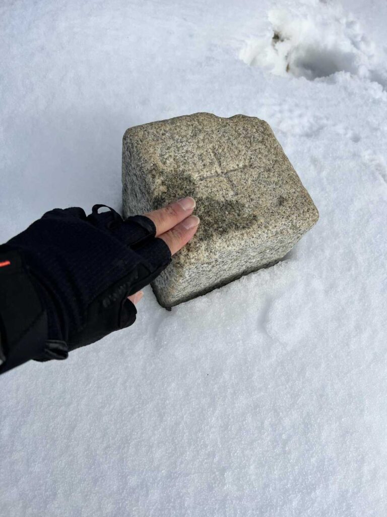 雪に埋もれた山頂の三角点